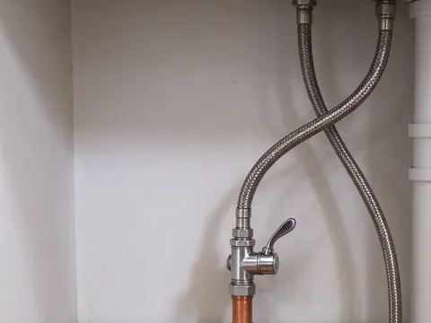 New chrome angle stop and braided supply line under a sink