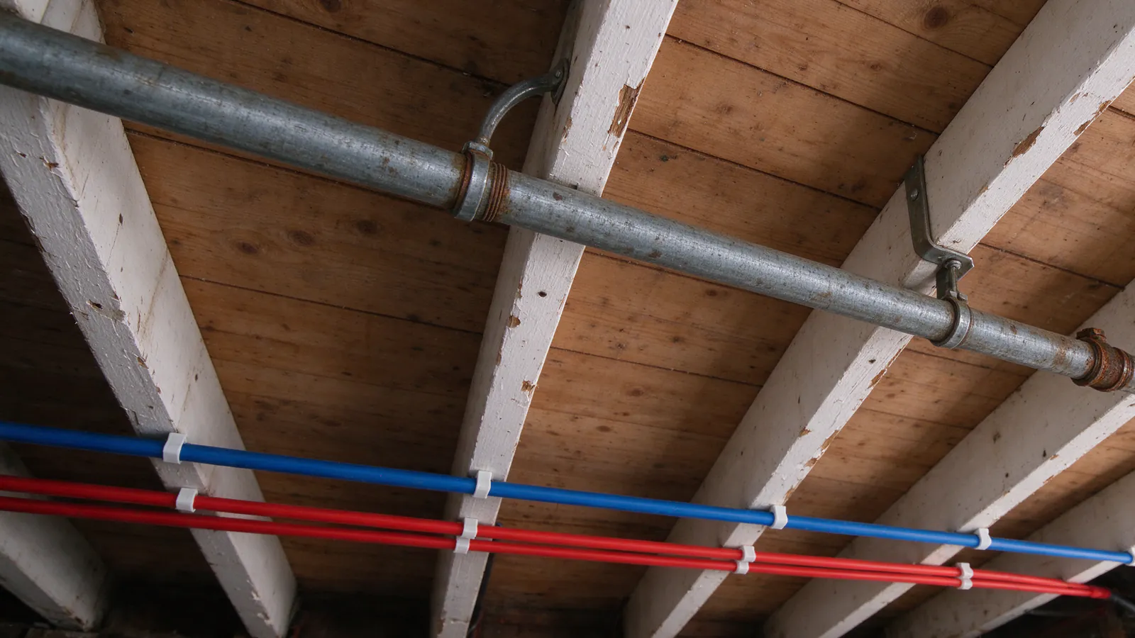 Old galvanized main beside its new PEX replacement on garage ceiling joists