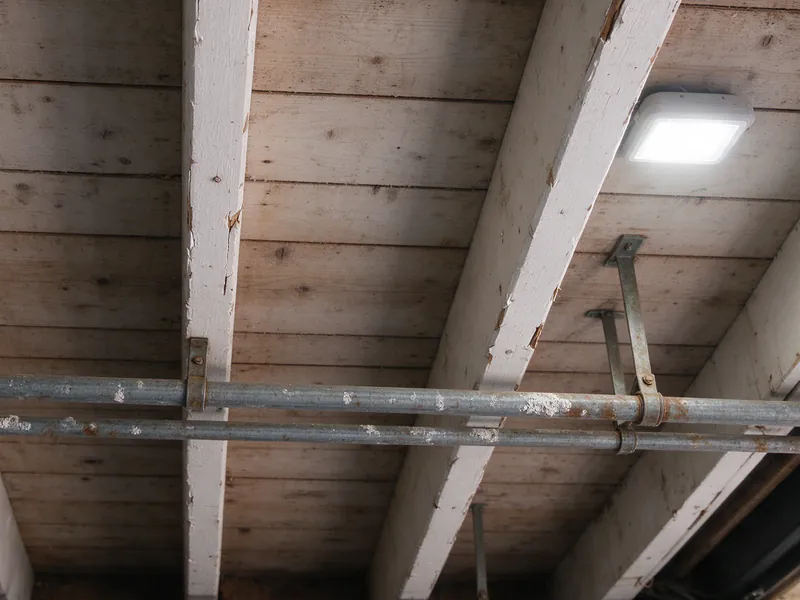 Old galvanized water lines hung across the joists of a San Francisco garage ceiling