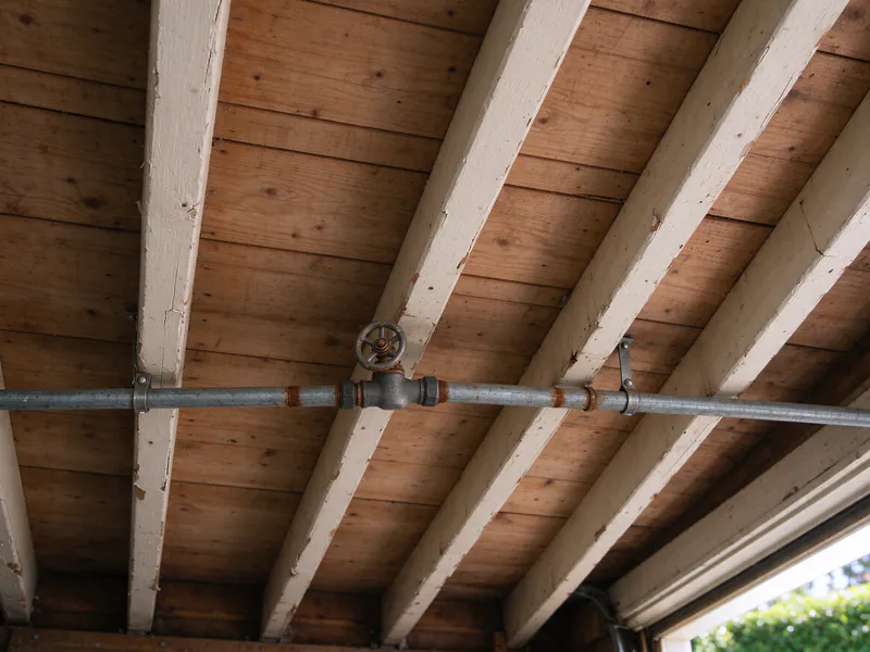 Old galvanized water main with a gate valve across the joists of a San Francisco garage ceiling