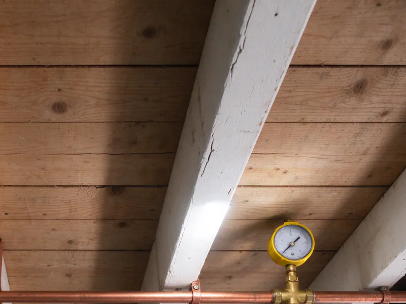 Pressure test gauge on a new copper water main across the joists of a San Francisco garage ceiling