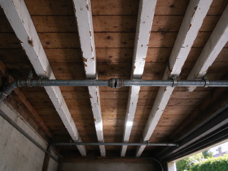 Split coupling dripping water on an old galvanized line across garage ceiling joists